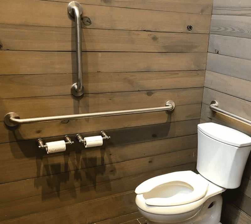 Brushed grab bar on wood-look wall beside toilet