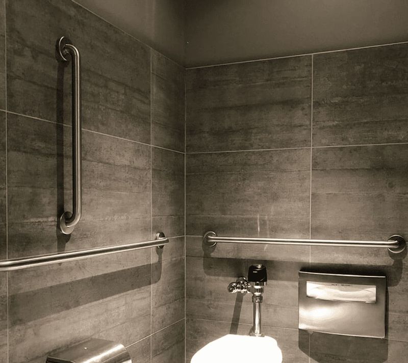 Brushed stainless vertical and horizontal grab bars on grey tile