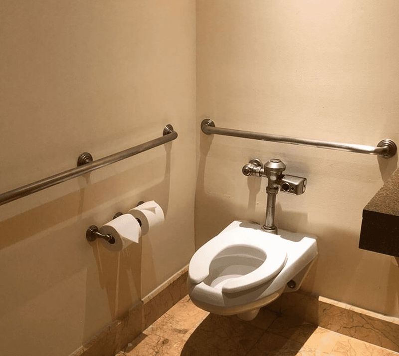 Polished stainless grab bars beside a toilet